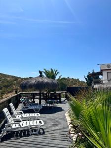a deck with chairs and a table with a straw umbrella at Cabañas las Balsas Rapel in Las Cabras