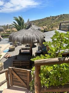 a straw umbrella and chairs and a fence at Cabañas las Balsas Rapel in Las Cabras