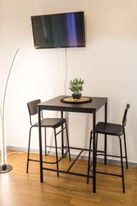 een zwarte tafel met twee stoelen en een tv aan de muur bij Charmant studio avec Parking privé - Proche Part-Dieu in Villeurbanne