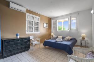 Schlafzimmer mit einem Bett, einem Stuhl und Fenstern in der Unterkunft Villa Rêve du Rocher in Le Diamant