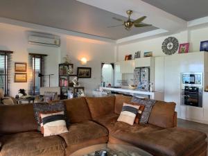 Maison d'exception في Nathon Bay: غرفة معيشة مع أريكة بنية ومطبخ