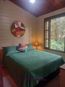 a bedroom with a bed with a green comforter and a window at Casa e kitnet Morada Aguiar - casa in Abraão