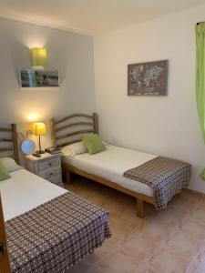 a room with two beds and a table with a lamp at Chalet con piscina en Menorca in Cala en Bosc