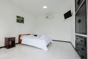 Cette chambre blanche comprend un lit et une table. dans l'établissement Hotel Pelican Bay, à Puerto Ayora