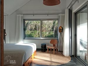 um quarto com uma cama, uma janela e uma cadeira em Casas do Morgadio em Biscoitos
