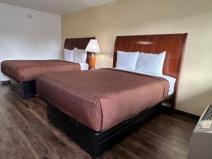 a hotel room with two beds and a lamp at Desert Sands Inn & Suites in Albuquerque