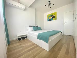 a white bedroom with a large white bed and wooden floors at Unique Sea View in Varna City
