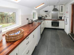 a kitchen with white cabinets and a wooden counter top at Rose Villa in Builth Road