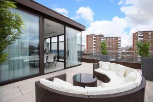 a balcony with a white couch and a table at Stunning 3 Bedroom Penthouse Private Terrace AC in London