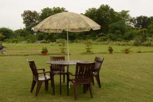 a table and chairs under an umbrella in a field at Hotel Radha Rani Mahal in Khajurāho