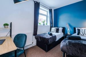 a blue room with two beds and a chair at Cozy and Stylish 1 Bedroom Flat in Warrington in Warrington