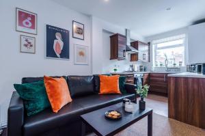a living room with a black leather couch and a kitchen at Cozy and Stylish 1 Bedroom Flat in Warrington in Warrington