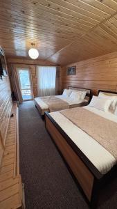 a bedroom with two beds in a wooden cabin at Порядна Ґаздиня in Yaremche