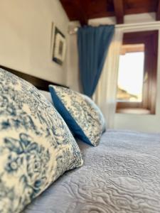 a bed with blue and white pillows and a window at Porto Valentino Apartment in Sirmione