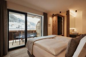 a bedroom with a bed and a balcony with a table at Chalet Milé in Ortisei