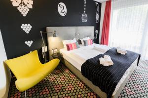 um quarto com uma cama e uma cadeira amarela em Hotel Bonvino Badacsony em Badacsonytomaj