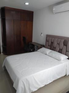 1 dormitorio con 1 cama blanca grande y escritorio en Apartaestudio 201 - Casa Hotel Anita, en Tuluá