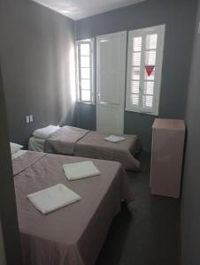 a hotel room with two beds and two windows at Hotel Rest in Porto Alegre