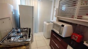a kitchen with a stove and a microwave at Portinari 2 in Rio das Ostras