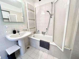 a white bathroom with a sink and a bath tub at Il Re di Torino [Zona Migliore della Città] in Turin