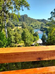 a wooden bench with a view of a river at El Arrayán in Lago Ranco