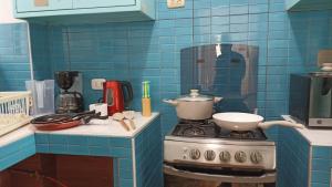 una cocina de azulejos azules con estufa y olla. en Miraflores Private Rooms - Guest House - Cocina Compartida - Terraza en Lima