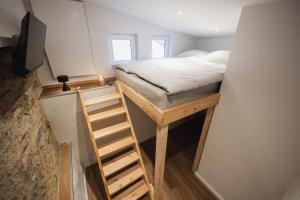een kleine slaapkamer met een bed en een ladder bij Tiny House mit Wohnfass in Diez