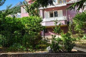 a pink house with a white balcony in a garden at PETAR in Baška Voda