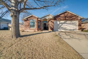 a house with a tree and a driveway at Saginaw Home with Fenced Yard 11 Mi to Fort Worth! in Saginaw