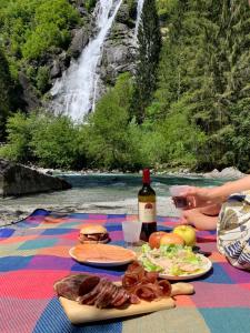 un tavolo da picnic con cibo, una bottiglia di vino e una cascata di Appartamento sci & laghi "Tre Fontane" a Tione di Trento
