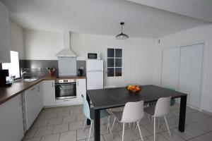een keuken met een zwarte tafel en witte apparaten bij Gite de la rue du château - tout inclus in Pontgibaud