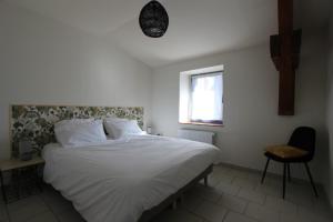 1 dormitorio con cama blanca y ventana en Gite de la rue du château - tout inclus en Pontgibaud