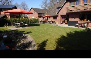 a house with a yard with chairs and tables and umbrellas at Hotel am Naturschutzpark in Undeloh