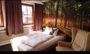 een slaapkamer met een bed en een stoel naast een raam bij Hotel am Naturschutzpark in Undeloh