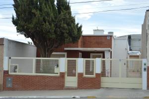 una casa in mattoni con una recinzione bianca e un albero di Espacio de la Patagonia a Comodoro Rivadavia