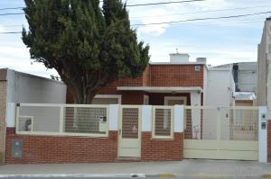 a brick house with a white fence and a tree at Espacio de la Patagonia in Comodoro Rivadavia