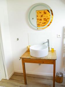 La salle de bains est pourvue d'un lavabo et d'un miroir sur une table. dans l'établissement Le Cinquante, à Groix