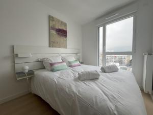 a white bedroom with a large white bed with two pillows at le Bel Alpin in Annecy