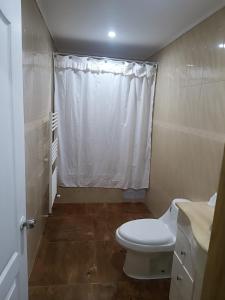 a bathroom with a toilet and a white shower curtain at Casa de Campo in Osorno