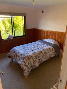 Un dormitorio con una cama con una manta. en Casa de Campo en Osorno