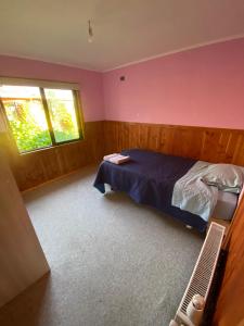 1 dormitorio con cama y ventana en Casa de Campo, en Osorno