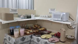 a shelf with a bunch of pastries and a microwave at Guarujá Praia Hotel Econômico in Guarujá