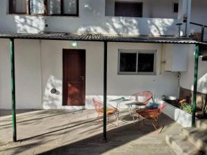a patio with a table and chairs and a door at Alojamiento frente al Arroyo Cristal in Tanti +13 photos