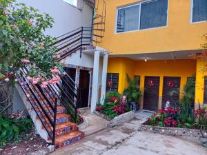 a yellow and white house with a staircase and flowers at Casa Amelia in San Blas