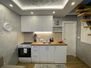 a kitchen with white cabinets and a sink at Apartman Marsalforn in Veternik