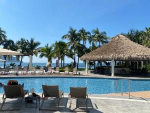 una piscina en un complejo con sillas y sombrillas en Departamento a pie de playa en Camino al Mar, en Mazatlán