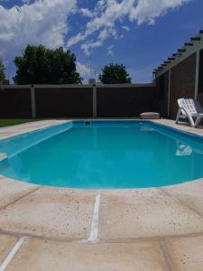 a large swimming pool with a chair in a yard at Hermosa casita con quincho y amplia pileta TODAS LAS COMODIDADES Paz total in Ullún
