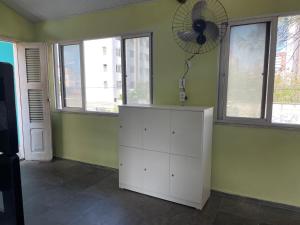 Zimmer mit einem weißen Schrank und einem Ventilator an der Wand in der Unterkunft Salve Maloca Hostel in Fortaleza