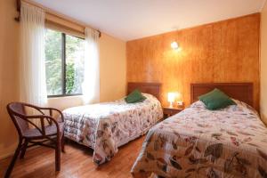 a bedroom with two beds and a chair and a window at Cabaña Vaenga Miro in Hanga Roa