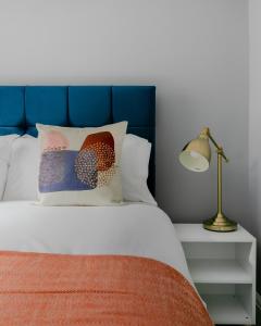a bed with a blue headboard and a pillow and a lamp at Homely 3 Bedroom House in Hammersmith in London